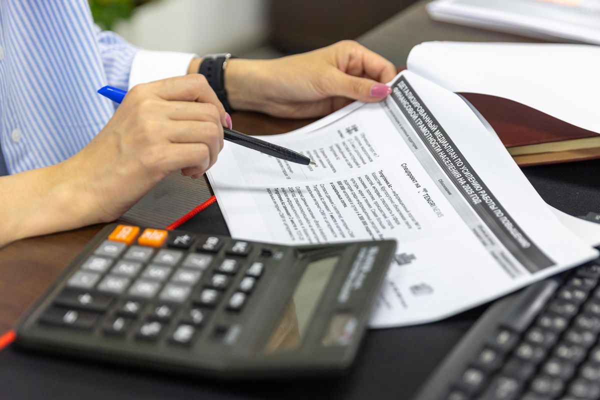 Close-up of financial review using a calculator and pen