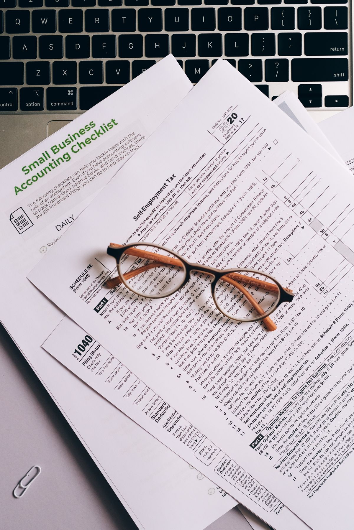 Documents and glasses on a laptop keyboard